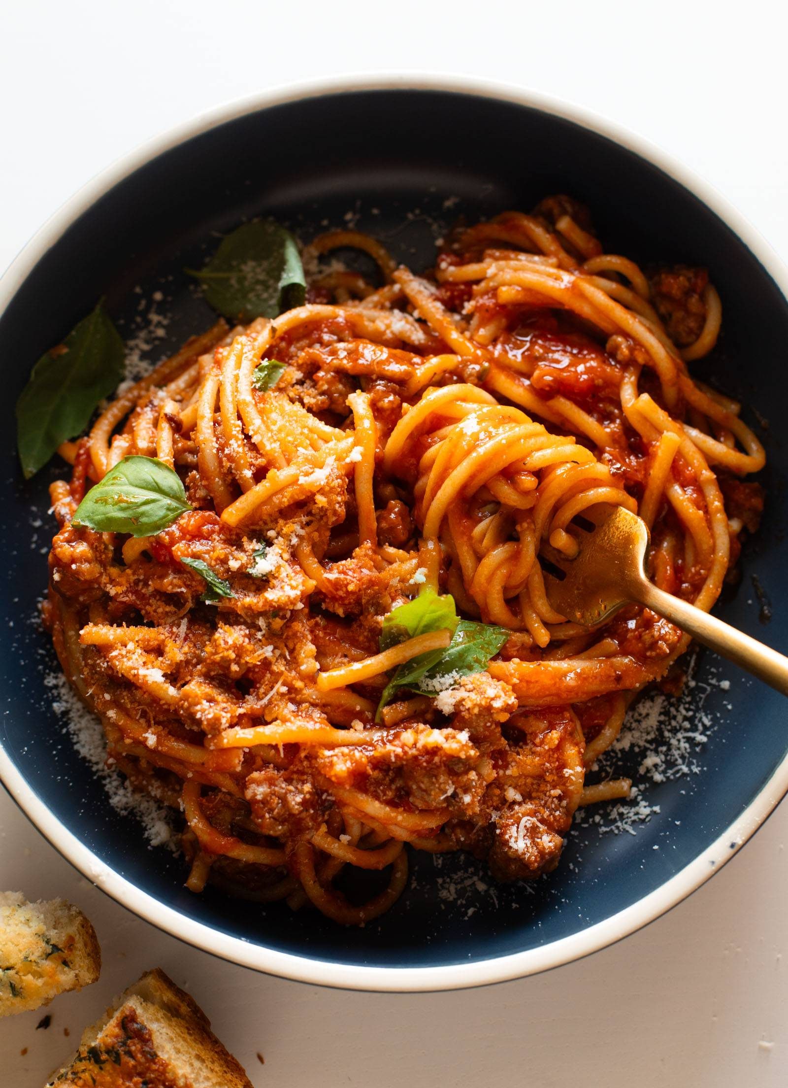Instant Pot Spaghetti in a bowl topped with basil and parmesan.