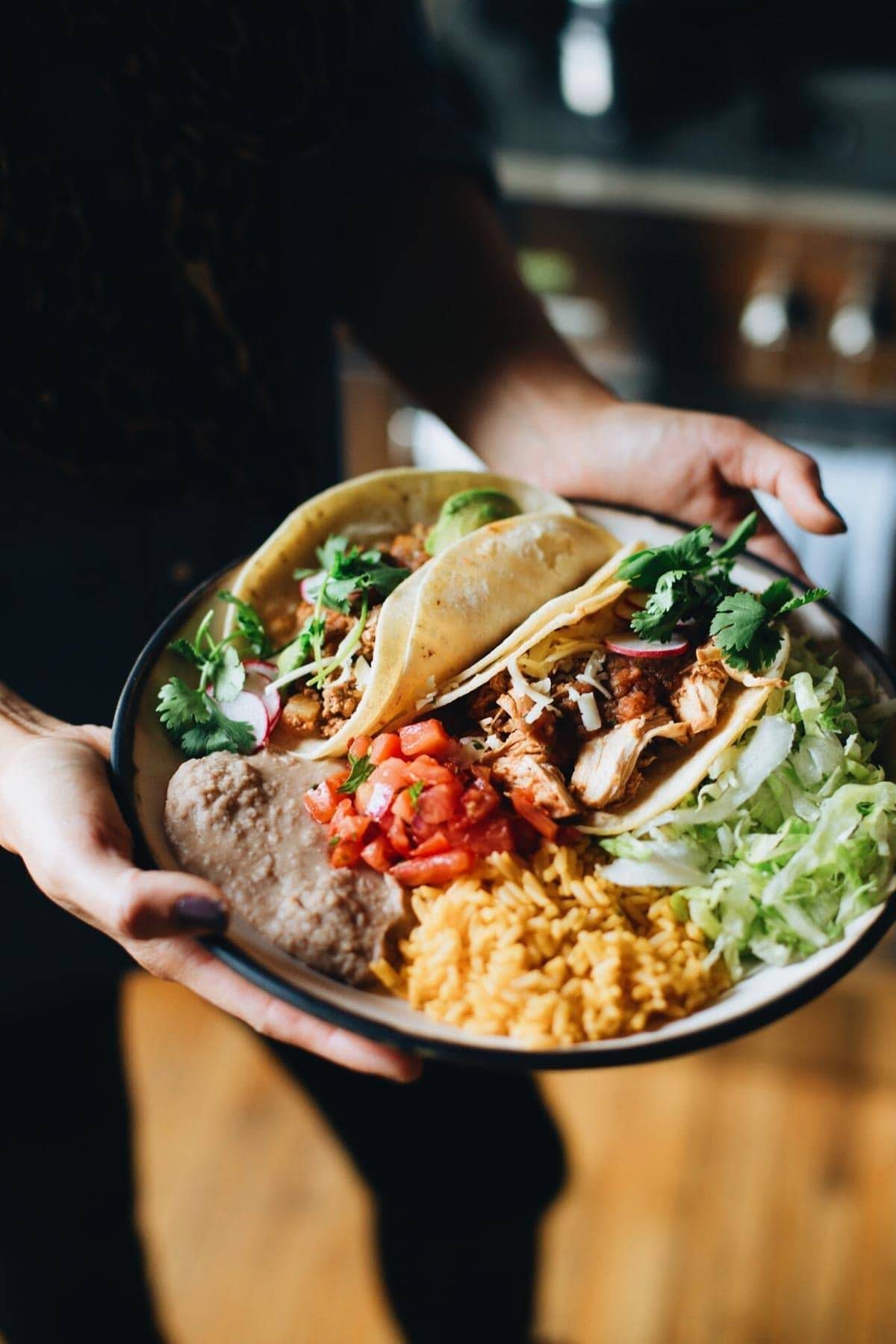 Hands holding a plate of food.